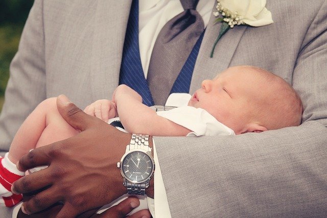 Aufgaben der Taufpaten. Mann mit Baby im Arm.