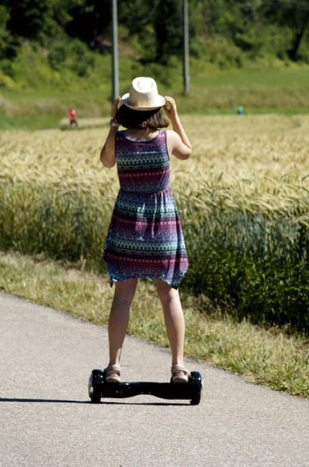 Kind mit Hoverboard auf dem Land.